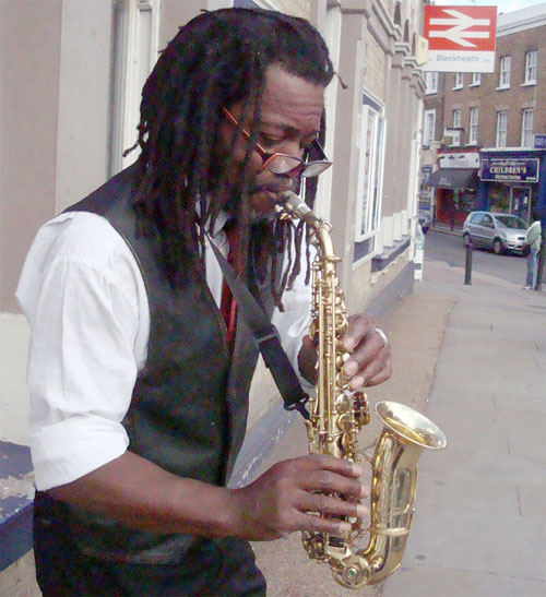 Saxophonist busker playing his sax outside Blackheath Station on a Sunday. Photo by Flickr user Julie70.
